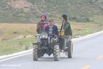 Tibetans driving a tractor on a highway