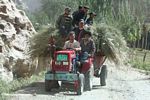 Group of Tajiks riding a hay-filled tractor