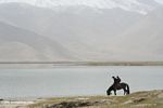 Father and son on horseback on the shore of Lake Karakul