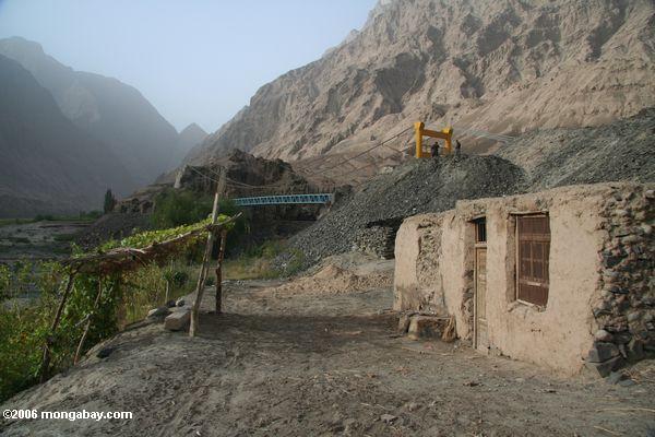 Tajik Ziegelsteinhütte mit Brücke und Bergen nach