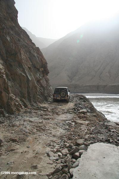 Felsige Straße entlang einem Fluß in den Kunlun Bergen