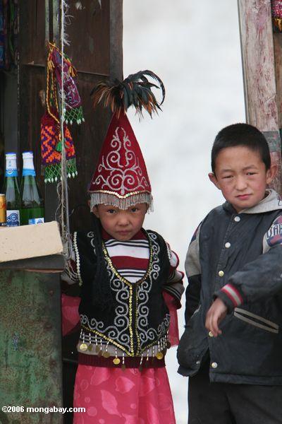 Chinesisches Mädchen und der Junge, die an einer Süßigkeit und an einem Soda arbeitet, stehen entlang der Karakoram Landstraße