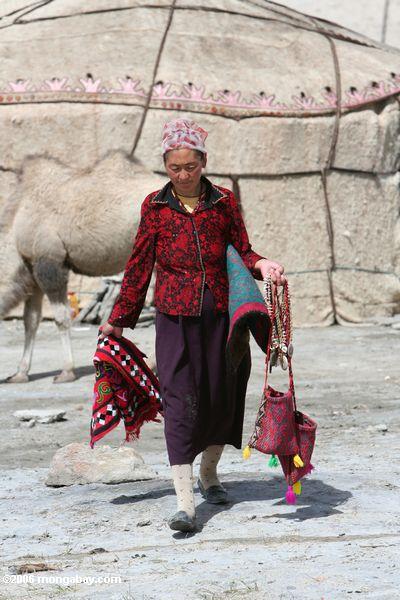 Mulher de Tajik que anda com os bens para a venda