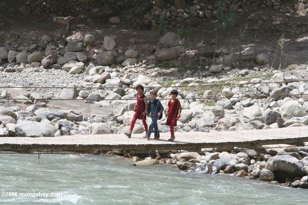 Tajik kids die Kreuzung von einem Fluß durch Brücke