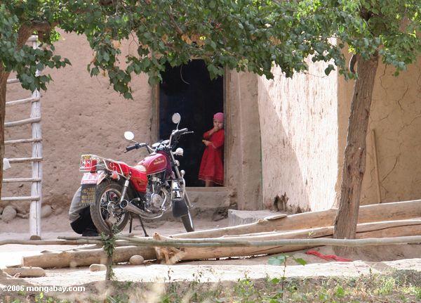 Kind, das in einem Eingang hinter einem Motorrad Xinjiang
