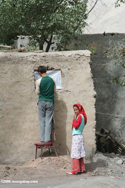 Das Reparieren eines Fensters in Kusrap bemannen, während eine Frau, die unter Xinjiang