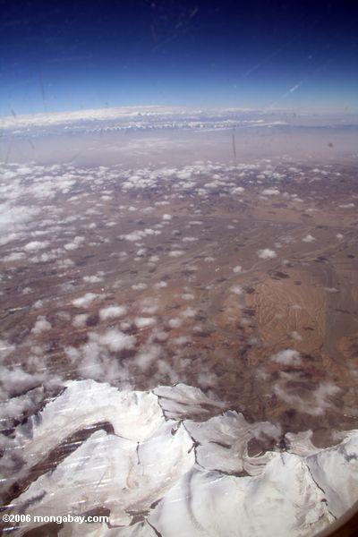 雪をかぶった山々や砂漠の飛行機ビュー中国西部で