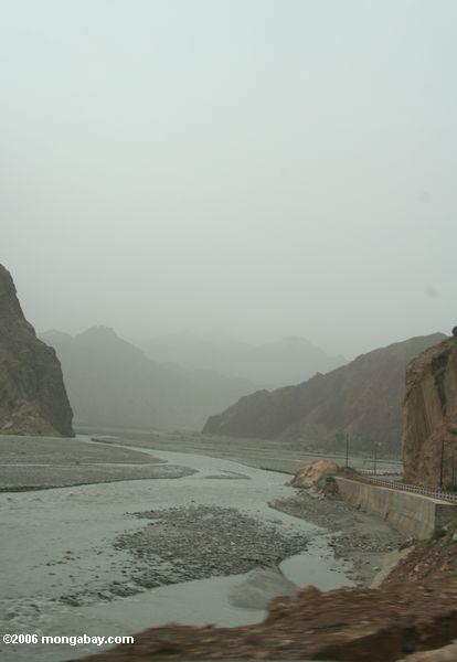 Karakoram Landstraße, die einem flachen Fluß Xinjiang