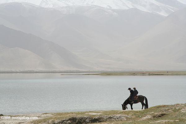Vater und Sohn an zu Pferde auf dem Ufer von See Karakul