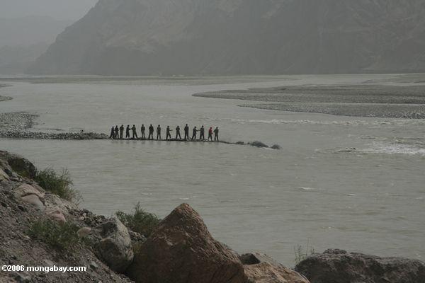 мужчины пытаются отвлечь река на западе Китая