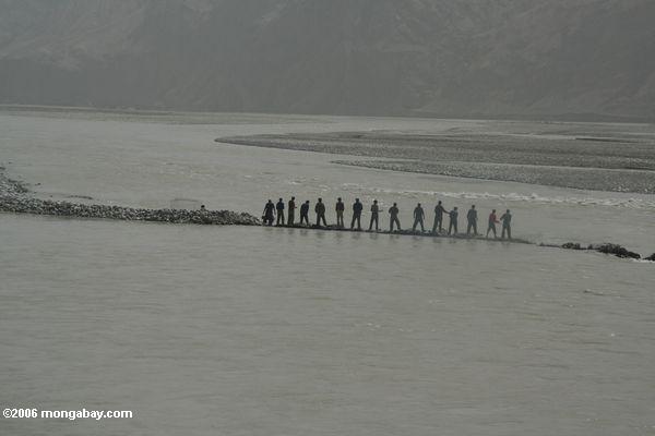 Männer, die versuchen, einen Fluß in Xinjiang Xinjiang