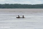 Two men in a dugout canoe on the Amazon river