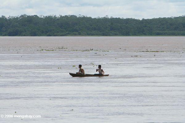アマゾンの川に丸木舟で2人の男性