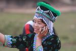 Hmong girl in traditional apparel talking on a mobile phone while playing pov pob