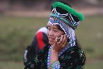 Hmong girl in traditional apparel talking on a mobile phone while participating in a traditional courtship game