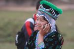 Hmong girl in traditional apparel talking on a mobile while participating in a traditional courtship ritual