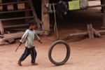 Boy pushing a tire with a stick