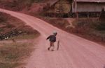 Boy pushing a bicycle tire down a road with a stick