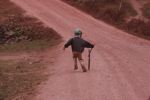Boy pushing a bicycle tire down a road with a stick